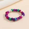 Dettaglio di un anello elastico colorato con perline viola, verdi e magenta vibranti - Serie Viola Patchwork
