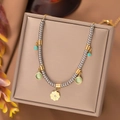 Macro shot of silver beaded necklace with golden flower and green gemstone charms - H1002 Necklace Gold