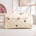 Detail of cream quilted makeup bag with black bow embroidery and dual zippers - Embroidered Bow Beige