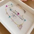 Vista macro di perle colorate in vetro a fragola e pendente in cristallo su collana - Stile Pendente a Fragola Colorato