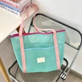 Close-up of mint green mesh beach tote bag with pink canvas straps and blue front pocket - Green