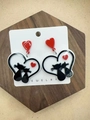 Detail of acrylic heart earrings featuring black and red cats on a wooden coaster - Two Cats in Heart