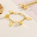 Gros plan du bracelet géométrique doré avec pendentifs cube et feuille sur fond aux tons chauds - Style Pendentif Géométrique (KB169300-HG)