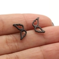 Macro shot of black stainless steel hollow wing earrings held by hand for scale - 672 Angel Wings / Black