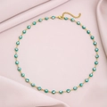 Close-up of golden stainless steel necklace with green enamel evil eye beads detail - Green