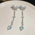 Detail of silver tassel earrings featuring blue heart stones and butterfly design - Light Blue