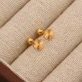 Boucles d'oreilles trèfle dorées en acier titane avec texture radiale sur présentoir - Trèfle Texturé