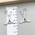 Silver vintage sports alloy hockey stick and ball charms with a ruler for size scale - Crossed Hockey Sticks