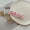 Détail du peigne à fleurs rose en acrylique sur un plateau décoratif dans un cadre esthétique - Rose