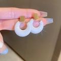 Elegant gold square stud earrings with white round drop pendants shown in hand - White Drip Circle