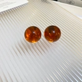 Primer plano de pendientes de bola de resina ámbar con superficie pulida y brillo suave - Pendientes de Botón Redondos de Resina Café / Marrón