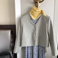 Close-up of a light green short blazer and yellow plaid neck scarf on a metal hanger - Yellow