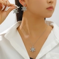 Close-up of elegant silver snowflake jewelry set with micro-diamonds on a female model - 26 Earrings + Necklace Style