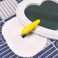 Vibrant yellow simulation corn hair clip with black duckbill base on white plate - Corn