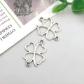 Close-up of two silver-tone antique alloy hollow clover pendants for DIY jewelry making - Double Hook Heart Four-leaf Clover 14x17mm