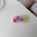 Macro detail of gummy bear hair clips in gradient resin pink, purple, blue, and yellow-green - Multicolor