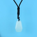 Macro shot of translucent white hexagonal crystal pendant with black braided rope cord - Opal