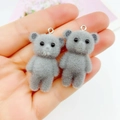Close-up of grey flocked mini bear charms with silver metal rings held in a hand - Grey Bear