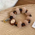 Detalle de pulsera con colgante de oso de madera y pompón en una bandeja beige - Colgante de Dibujos Animados / Café Claro
