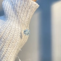 Détail du pendentif flocon de neige avec pierre bleue sur modèle en pull blanc - Flocon de Neige Bleu Clair/Chaîne Argentée