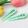 Dettaglio di due fermagli per capelli a onda verde menta su sfondo bianco con tulipani - verde chiaro