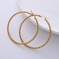 Macro detail of 50mm gold-plated twist rope hoop earrings on white ceramic dish - Gold