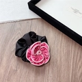 Vue détaillée d'un chouchou élégant en satin avec camélia noir et rose fuchsia - Rose Rouge