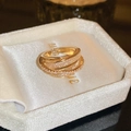 Close-up of multi-layer crisscross gold ring with pavé zircons in a jewelry box - Open Multi-layer Intertwined Style / Gold