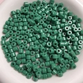 Macro shot of 6mm green cylindrical acrylic beads for handmade jewelry in a white container - Dark Green