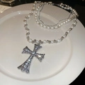 Primer plano de un collar con colgante de cruz brillante y perlas en porcelana - Plateado