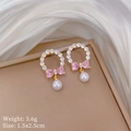 Detailed close-up of pink bow earrings with white pearls on elegant silk background - Bow Pearl Stud Earrings (D342)
