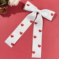 Détail du nœud de cheveux en satin blanc avec cœurs rouges 3D et longs rubans - Blanc