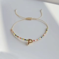 Nahaufnahme des böhmischen Perlenarmbands mit goldenem P-Anhänger und Webkordelzug - Buchstabe P