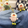 Close-up of colorful plush duck keychains in pink, green, and brown on denim fabric - Pink