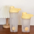 Yellow protein shaker bottle set with mixing ball and scale on wooden table - Yellow