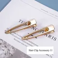 Paar minimalistische gouden driehoekige haarspelden op een trendy tijdschrift - Nr. 11 Accessoire haarspeld