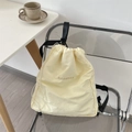 Dettaglio dello zaino a coulisse giallo crema con logo ricamato e texture in tela - Beige