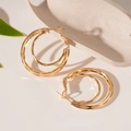 Close-up of double-layered geometric gold hoop earrings with textured outer ring detail - Gold (Silver Needle)