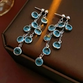 Detailed close-up of teardrop earrings with blue gemstones and dangling silver chains - Silver Blue Bezel Set Faceted Tassel Style
