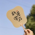Handheld fan featuring black calligraphy Luck characters with a light khaki finish - Always Lucky