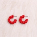 Exaggerated matte red twisted C-shape hoop earrings on white plush background - Small Red Twisted