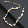 Dettaglio del bracciale dorato con ciondoli a stella blu e zirconi trasparenti lucidi - Blu