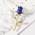 Elegante spilla rosa blu con stelo dorato e cristalli scintillanti su sfondo bianco - Blu