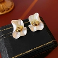 Dettaglio macro di orecchini a fiore bianco opaco con centro dorato su scatola vintage - Stile Fiore Rotondo Pieghettato / Perno d'Argento - Bianco - Oro