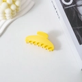 Detail of a vibrant yellow acetate hair claw clip in a stylish shell shape design - Yellow