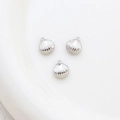Detailed view of three silver shell-shaped pendants with small loops on white ceramic - 9# Silver Shell