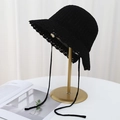 Close-up of black knitted bucket hat with lace-up bow and scalloped edge on gold stand - Black