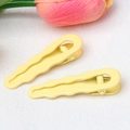 Detail of two yellow wavy matte hair clips with metal springs on a white background - Yellow