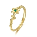Detail of adjustable gold ring featuring flower motif and green faceted gemstone - May