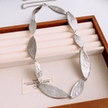 Macro detail of silver leaf-shaped metal chain featuring unique hammered texture finish - Silver